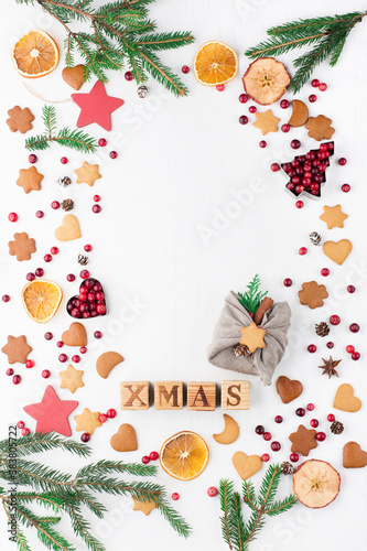 Christmas Decorative Border made of Festive Elements, gingerbread cookies, cranberries on white wooden background.