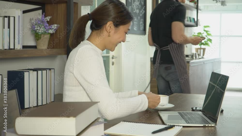 Attractive young Asian woman working on laptop in coffee shop.