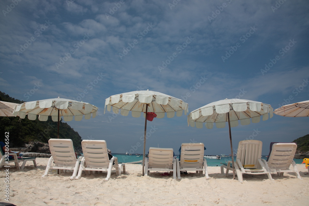 Tourists swimming and Snorkeling at beach with resort outdoor sunshade and chairs on the tropical island in Phuket, Thailand. 