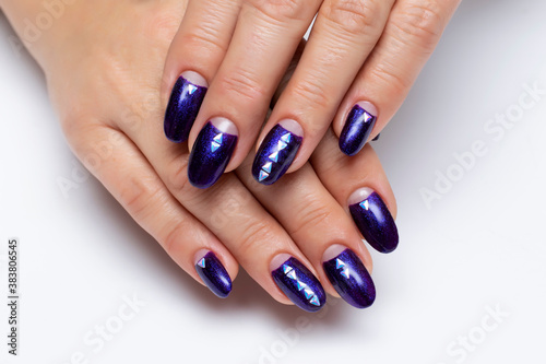 Dark Blue nacre manicure with crystals on long oval nails close-up on a white background. Shiny dark purple manicure.