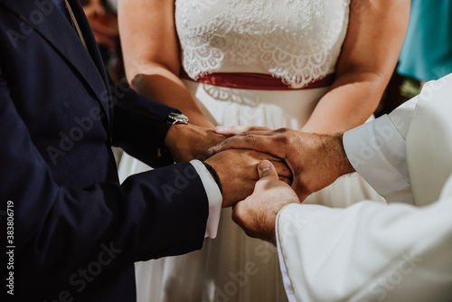 bride and groom holding hands. Couple consecrating their love at the altar with their hands joined and being blessed by the priest