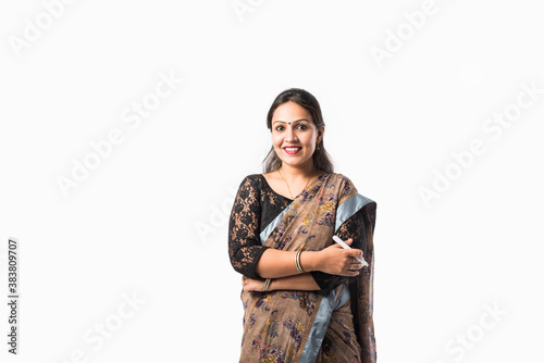 Portrait of asian Indian lady teacher in saree stands against writing board conducting online class
