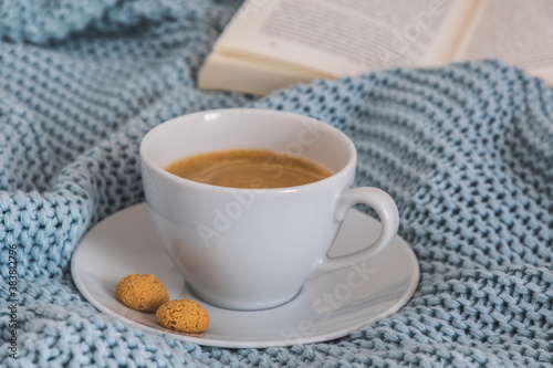 Cup of coffee on a light blue knitted wool blanket. Cozy atmosphere. Coffee break, stay at home concept.