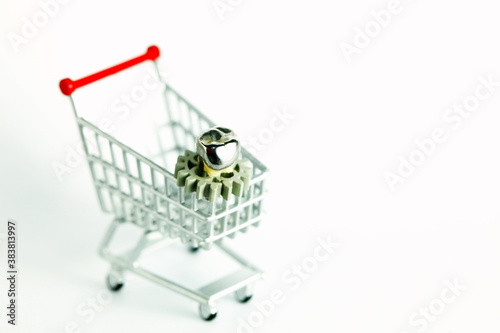 Miniature shopping cart model containing crown cap on tooth scene represent shopping concept related idea.