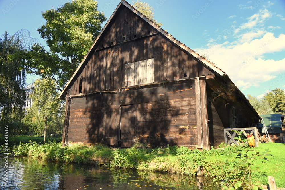 Holzhaus am Ufer eines Spreearmes vor strahlend blauem Himmel Holzhaus am Ufer eines Spreearmes vor strahlend blauem Himmel