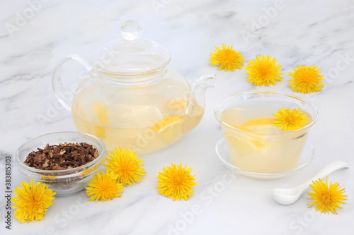 Immune boosting dandelion flower & lemon tea in a glass tea pot & cup with dried dandelion root. Lowers cholesterol, blood pressure and regulates blood sugar. High in antioxidants and vitamin c.   © marilyn barbone