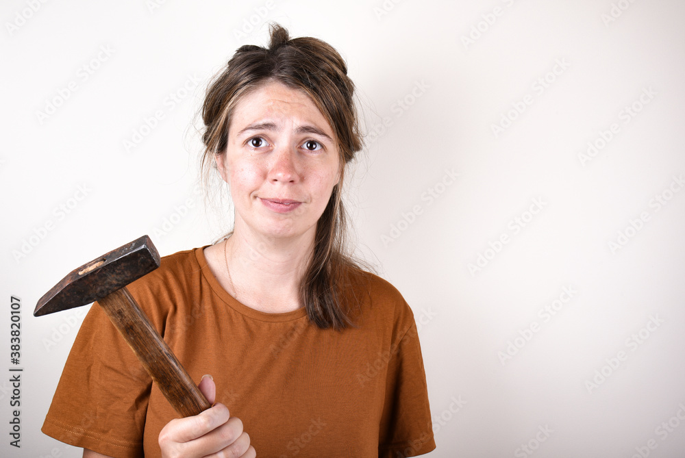 woman in brown T-shirt, holding hammer, looking at camera, isolated on white background. home renovation concept woman in brown T-shirt, holding hammer, looking at camera, isolated on white background. home renovation concept