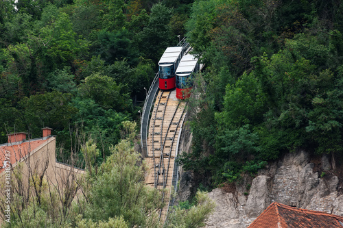 Modern funicular cars moving up and down the tracks. Way to Schlossberg and Graz city panoramic view.