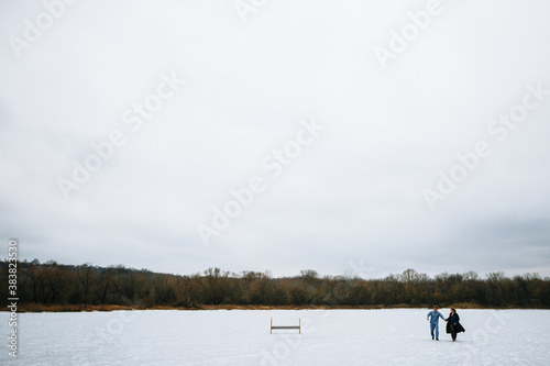 A guy and a girl in pajamas are on the ice of a frozen lake