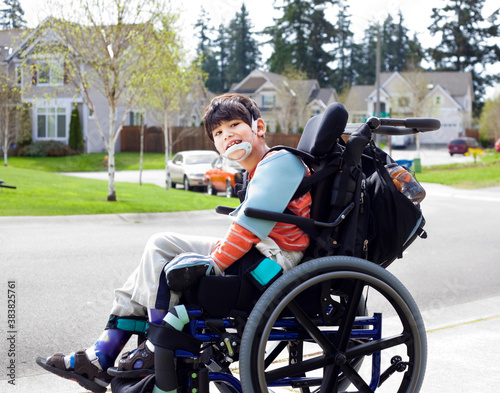 Happy disabled six year old boy waiting on sidewalk in wheelchai photo