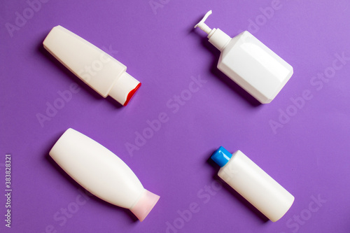 Set of White Cosmetic containers isolated on colored background, top view with copy space. Group of plastic bodycare bottle containers with empty space for you design