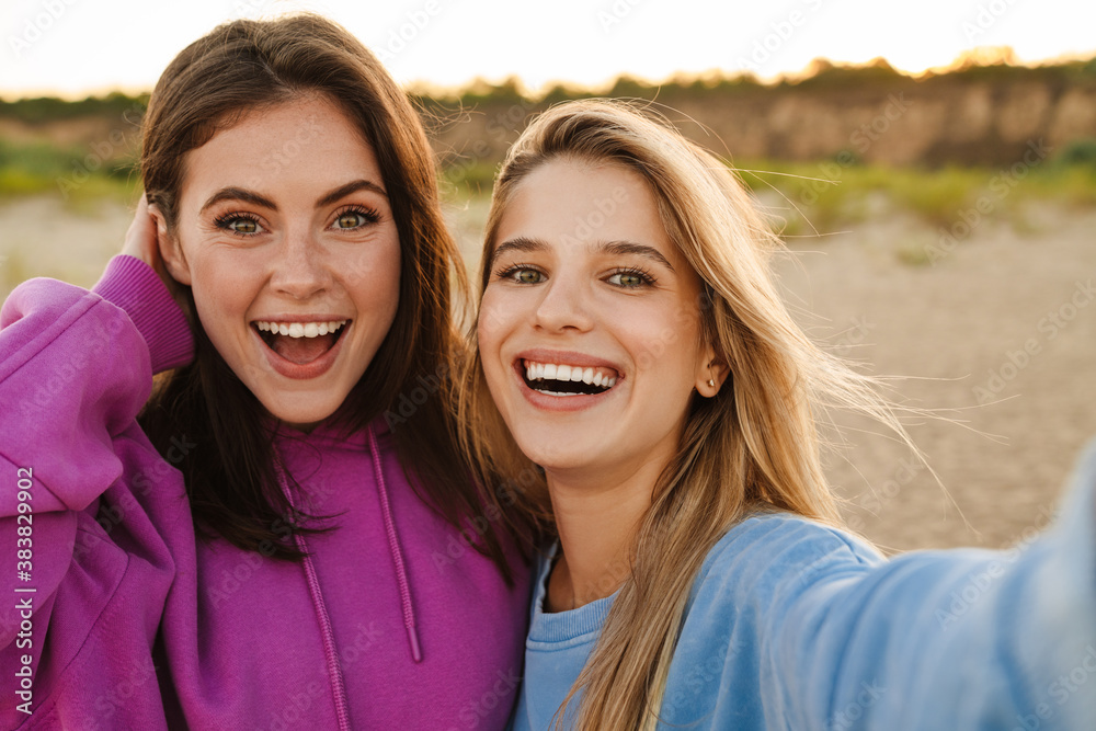 Two young caucasian women smiling and taking selfie photo on beach Two young caucasian women smiling and taking selfie photo on beach