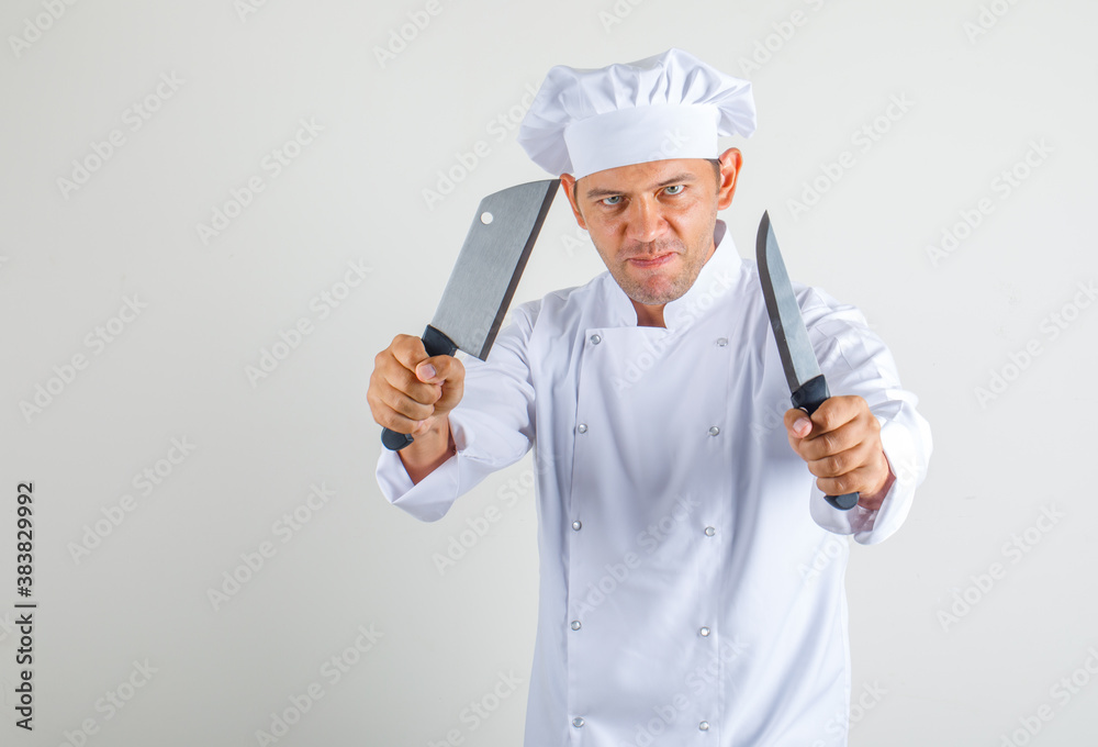 Male chef cook holding kitchen knives in uniform and hat and looking confident. front view. Male chef cook holding kitchen knives in uniform and hat and looking confident. front view.
