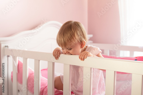 Baby girl standing in wooden crib
