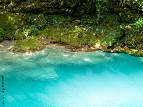 relaxing water stream with a green color, there is musk on the rocks and the water is a light turquoise color © infozoo