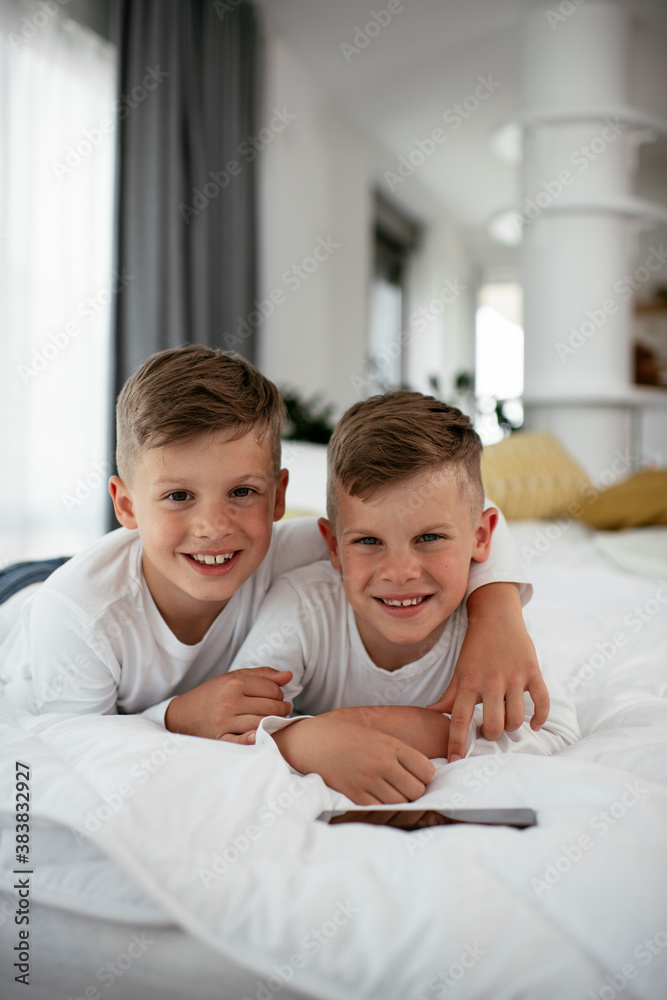 Two little brothers are playing games on the phone. Beautiful boys enjoying at home. Two little brothers are playing games on the phone. Beautiful boys enjoying at home.