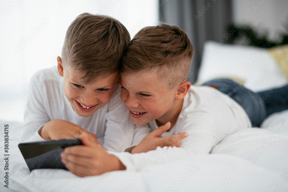 Two little brothers are playing games on the phone. Beautiful boys enjoying at home. Two little brothers are playing games on the phone. Beautiful boys enjoying at home.