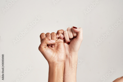 Close up of two female hands making a pinkie promise sign isolated over grey background. The symbol of commitment.