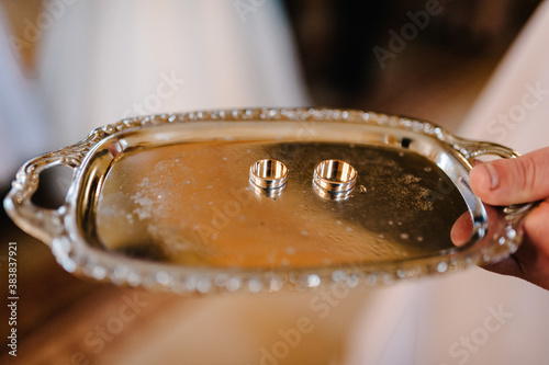 Tray with engagement wedding rings. Gold couple rings on a plate. wedding ceremony in christian church. close up. Selective focus. Photo in motion.