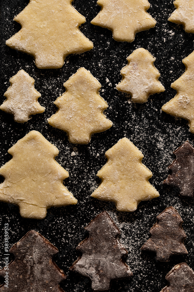 Pre-baked vanilla and chocolate Christmas cookies dusted with flour on the baking sheet Pre-baked vanilla and chocolate Christmas cookies dusted with flour on the baking sheet