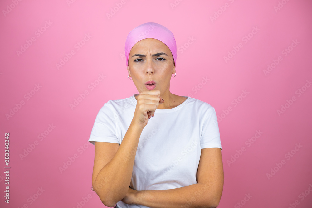 Young beautiful woman wearing pink headscarf over isolated pink background with her hand to her mouth because she's coughing Young beautiful woman wearing pink headscarf over isolated pink background with her hand to her mouth because she's coughing