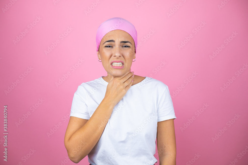 Young beautiful woman wearing pink headscarf over isolated pink background touching painful neck, sore throat for flu, clod and infection Young beautiful woman wearing pink headscarf over isolated pink background touching painful neck, sore throat for flu, clod and infection