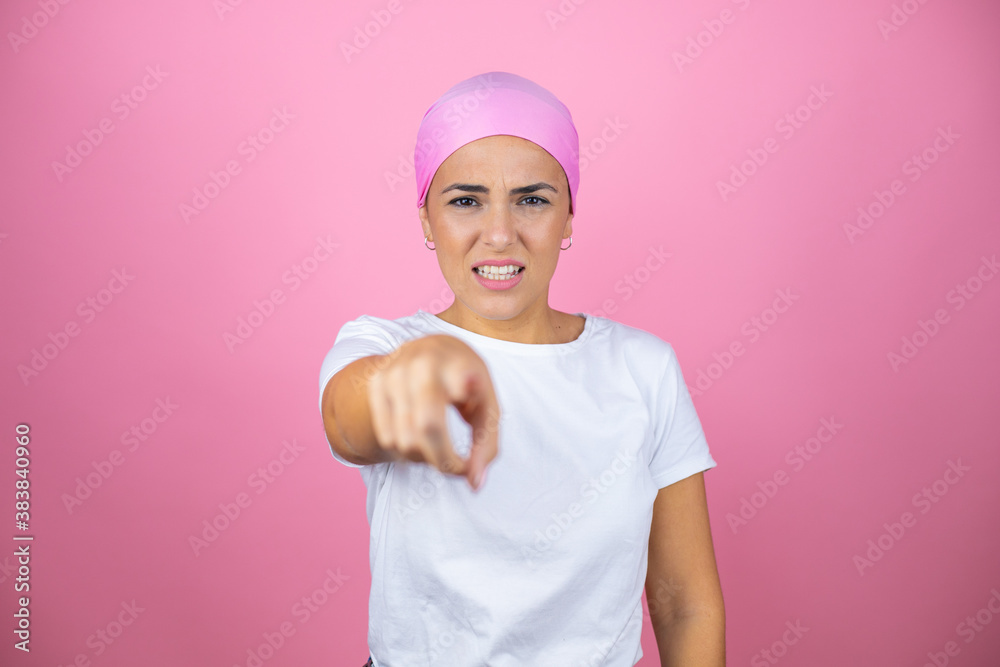 Young beautiful woman wearing pink headscarf over isolated pink background pointing with finger to the camera and to you, hand sign, gesture from the front
