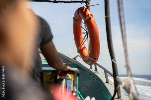 The right hand of the boatman and Orange Life buoy hanging on the boat at Redang Island, Terengganu, Malaysia photo