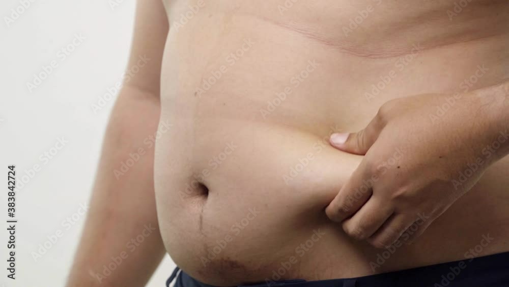 Close up of a big male stomach. The fat man checks his waist by left hand, he is obese and overweight isolated on white background. 4K Resolution. Close up of a big male stomach. The fat man checks his waist by left hand, he is obese and overweight isolated on white background. 4K Resolution.