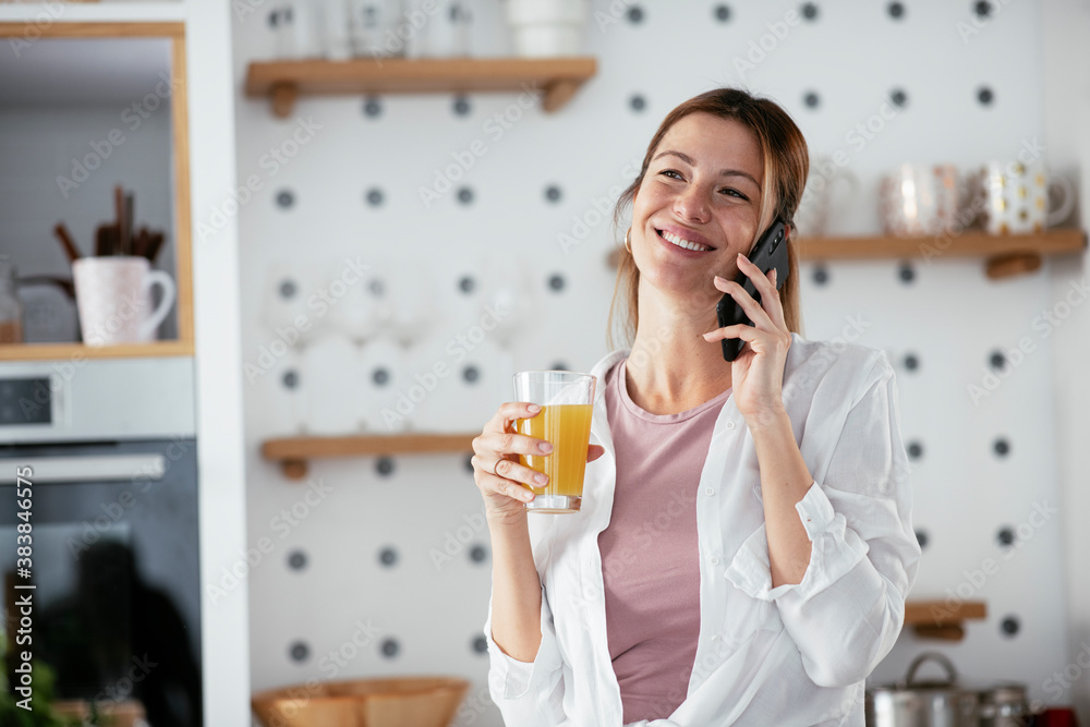 Young woman in kitchen. Beautiful woman drinkking juice and talking to the phone.. Young woman in kitchen. Beautiful woman drinkking juice and talking to the phone..
