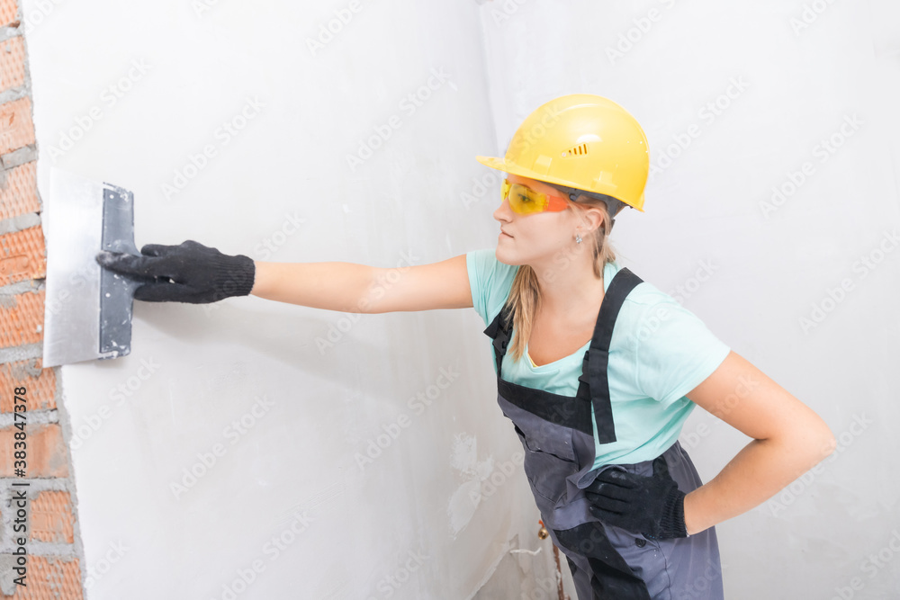 Female molar plasterer worker prepares the wall for applying plaster and leveling surface with spatula