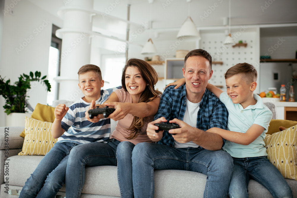 Husband and wife playing video games with joysticks in living room. Loving couple are playing video games with kids at home.. Husband and wife playing video games with joysticks in living room. Loving couple are playing video games with kids at home..