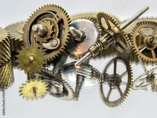 Gears on a light background. Copper gears of different sizes and shapes with reflecting backgrounds
