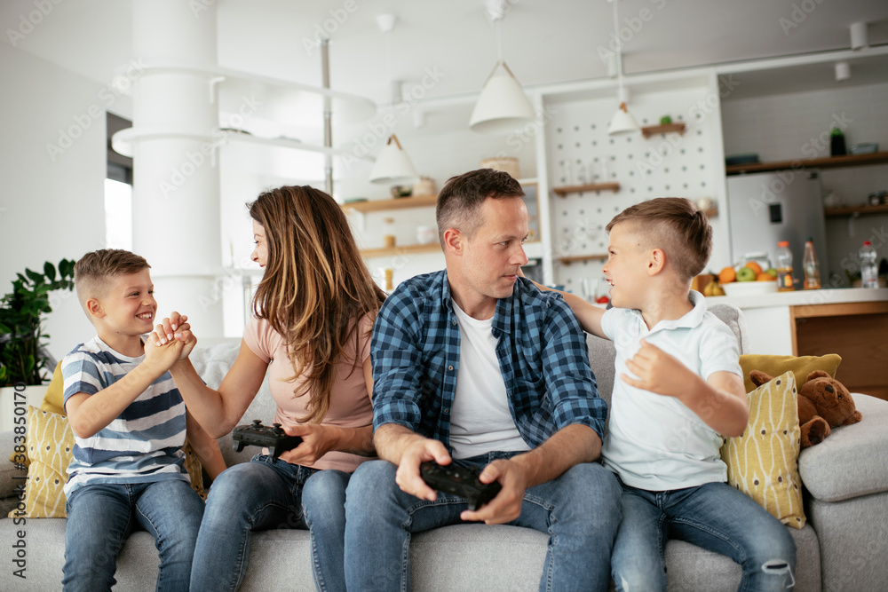 Husband and wife playing video games with joysticks in living room. Loving couple are playing video games with kids at home.. Husband and wife playing video games with joysticks in living room. Loving couple are playing video games with kids at home..