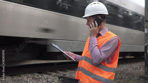 Railway engineer talking on the phone near the railway.