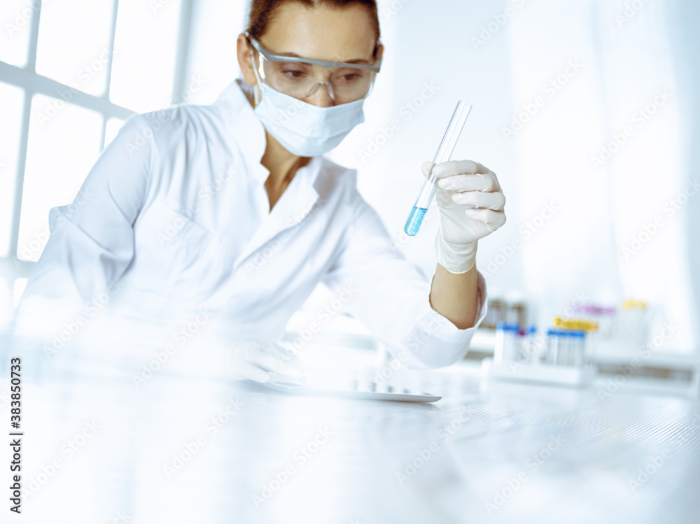 Female laboratory assistant analyzing test tube with blue liquid. Medicine, health care and researching concept Female laboratory assistant analyzing test tube with blue liquid. Medicine, health care and researching concept