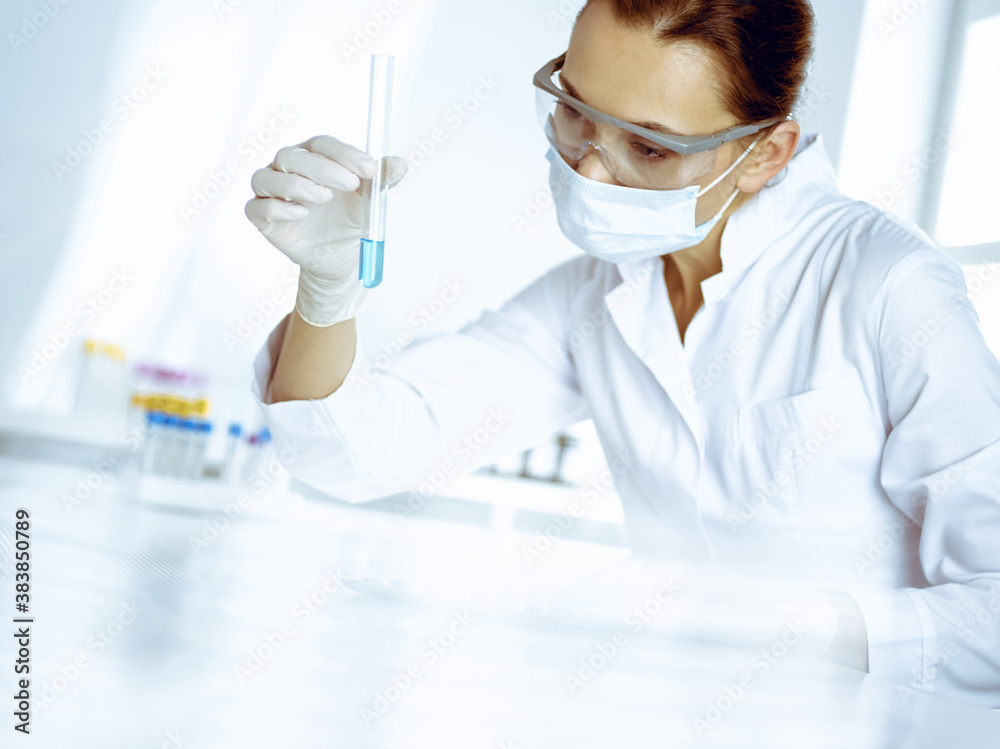 Female laboratory assistant analyzing test tube with blue liquid. Medicine, health care and researching concept Female laboratory assistant analyzing test tube with blue liquid. Medicine, health care and researching concept