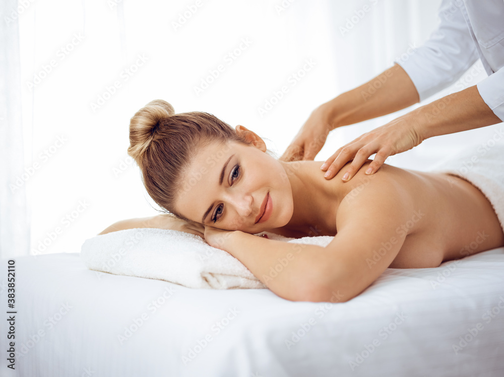Young and blonde woman enjoying massage of back in spa salon. Beauty concept Young and blonde woman enjoying massage of back in spa salon. Beauty concept