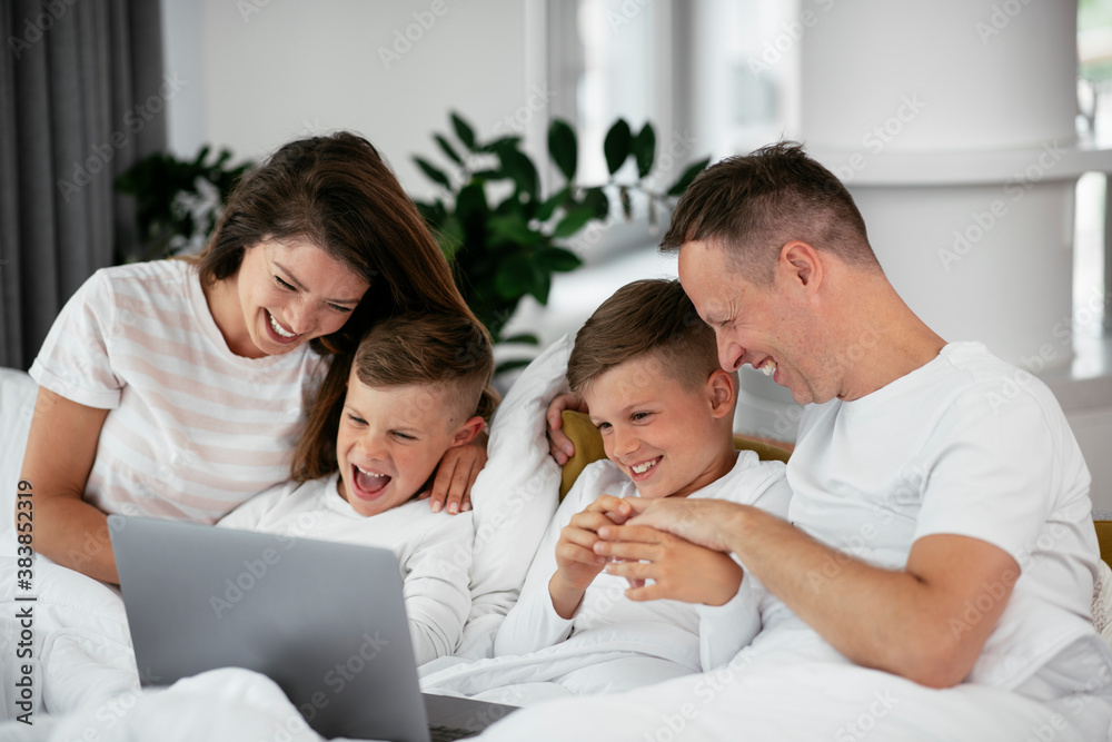 Beautiful parents with kids enjoying at home. Young family watching movie on lap top. Beautiful parents with kids enjoying at home. Young family watching movie on lap top.