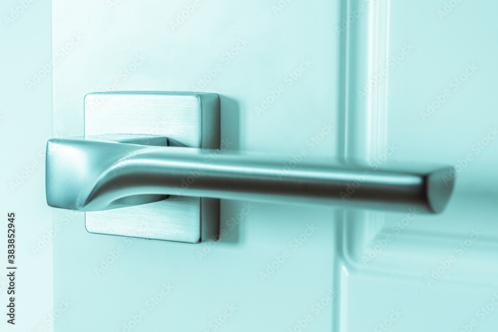 The silver metal doorknob is mounted in a white wooden door The silver metal doorknob is mounted in a white wooden door
