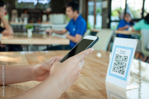 Women's hands are using the phone to scan the qr code to select food menu. Scan to get discounts or pay for food. The concept of using a phone to transfer money or paying money online without cash.