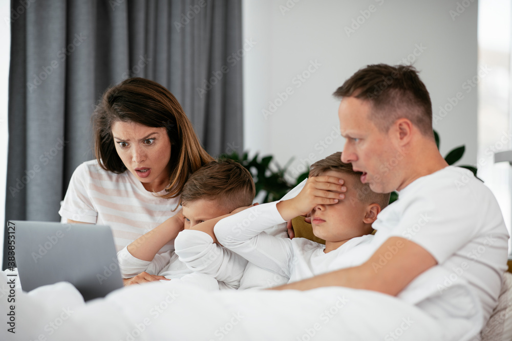 Beautiful parents with kids enjoying at home. Young family watching movie on lap top. Beautiful parents with kids enjoying at home. Young family watching movie on lap top.