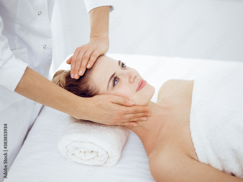 Young and blonde woman enjoying facial massage in spa salon. Beauty concept Young and blonde woman enjoying facial massage in spa salon. Beauty concept