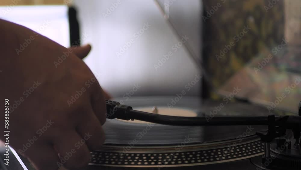 Close-up male hand starting record player, put  the needle on record, selective focus. Gramophone and record to listen to. Included turntable, arm and torque plate close-up on a light background. Sc D