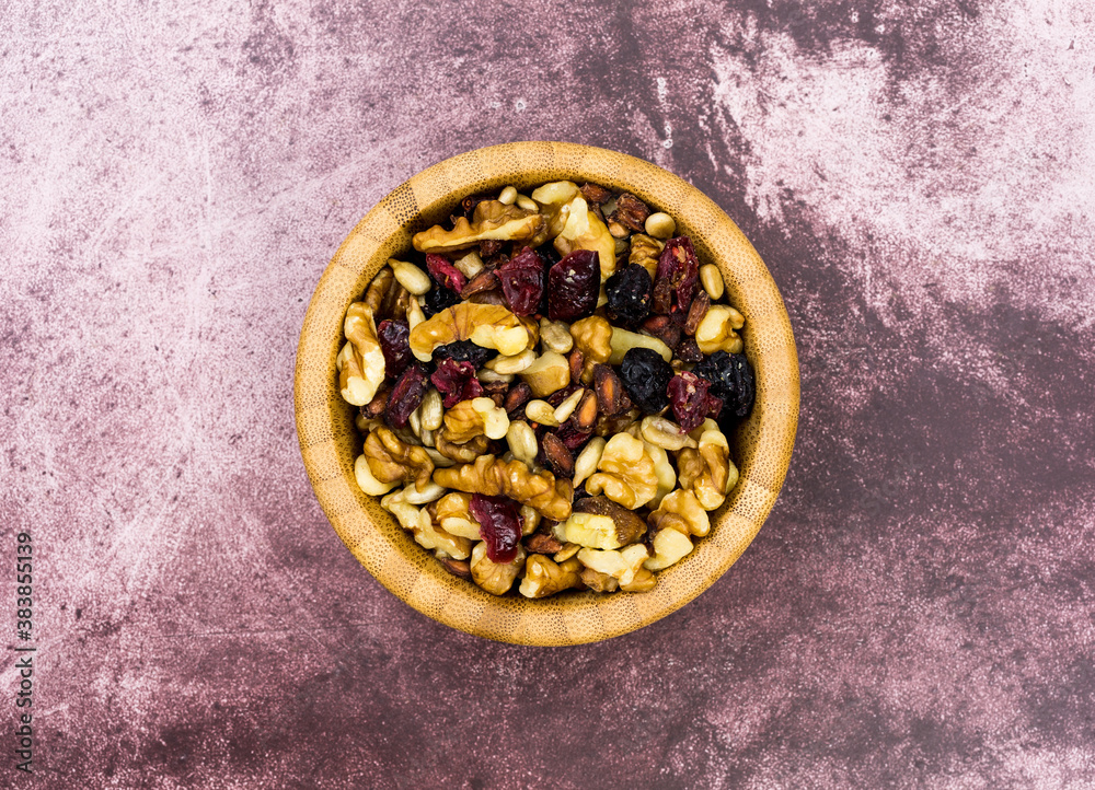Overhead view of a wood bowl filled with healthy trail mix on a tabletop. Overhead view of a wood bowl filled with healthy trail mix on a tabletop.