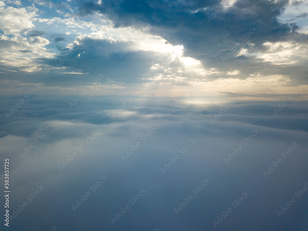 Aerial drone flight over the fog. There are thick clouds of fog below, the sun breaks through the clouds.