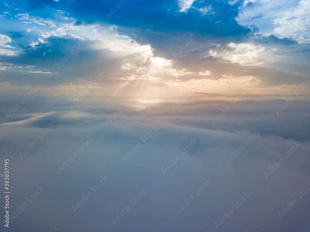 Obraz premium Aerial drone flight over the fog. There are thick clouds of fog below, the sun breaks through the clouds.