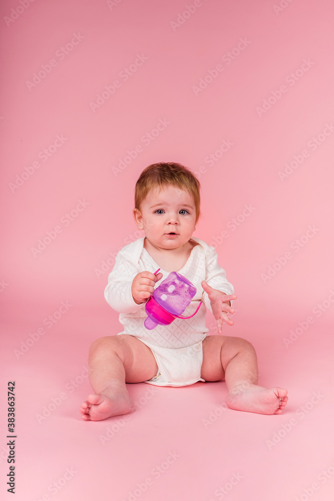 beautiful little girl on a white bodysuit sitting with a water bottle on a pink background with a copy of the space beautiful little girl on a white bodysuit sitting with a water bottle on a pink background with a copy of the space