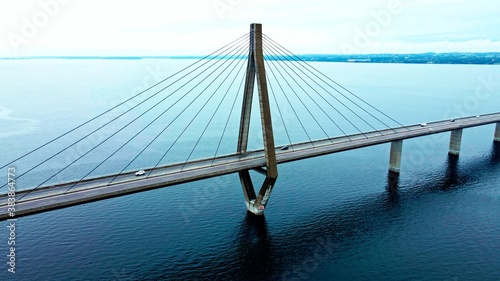 Large highway bridge spanning over a bay, with cars and trucks driving. Aerial view.