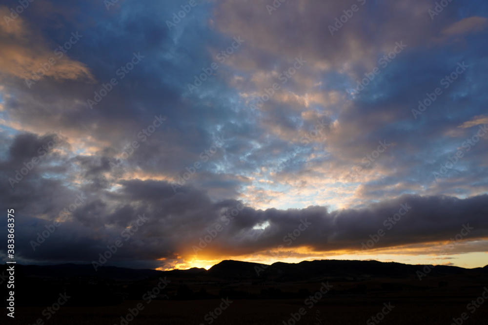 Landscape of mountains and fields with the sun back-lighting
